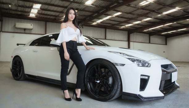 A slender Asian woman with long black hair wears a white off-the-shoulder top and black pants, posing beside a white sports car in a garage. photo