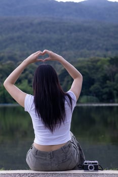 A woman sitting on a bench with her hands in the shape of a heart photo