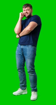 A man in a blue shirt and jeans poses confidently with a friendly smile against a bright green backdrop photo