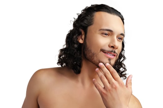 Young man with curly hair thoughtfully posing against a plain background photo