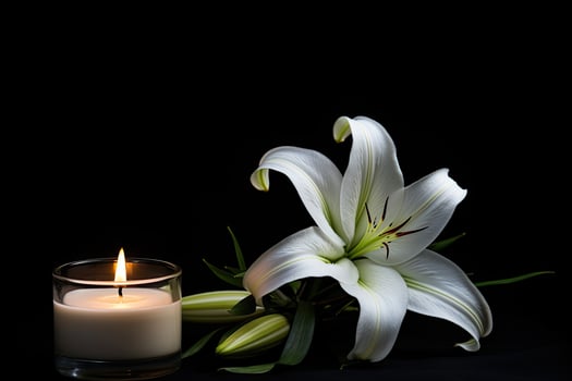 Elegant white lily flower and burning candle on black background photo