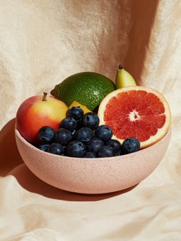 Healthy fruit bowl with blueberries, grapefruit, apple, lime and pear on beige fabric photo