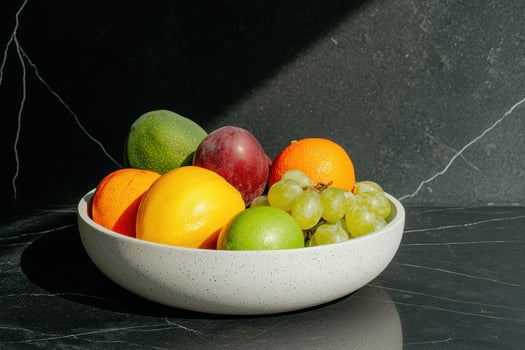 Fresh fruit in a speckled bowl on a dark marble surface photo