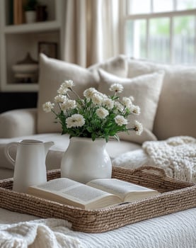 A white vase with flowers sits on a tray on a bed photo