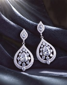 Luxurious silver drop earrings with diamond encrustations shine on black velvet under dramatic lighting photo