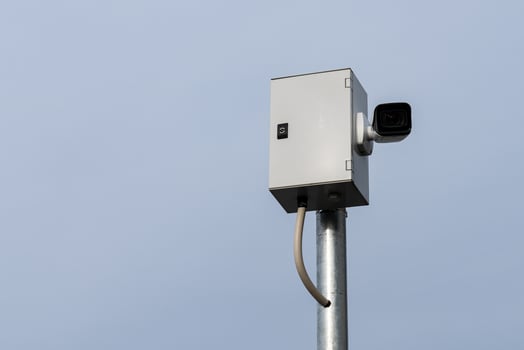 Security camera mounted on a metal pole against a clear sky photo