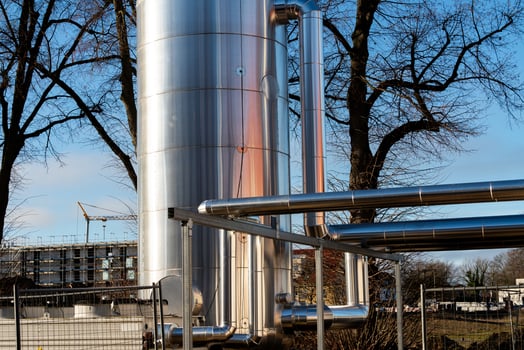 Industrial storage tank with metallic pipes against a clear blue sky photo