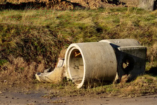 Concrete pipe and debris in overgrown grassy area. photo