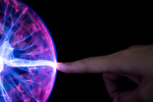 Finger touching plasma light ball on black background photo