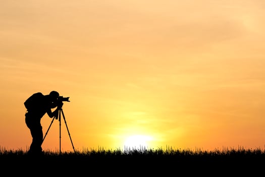 Silhouette of Photographer Capturing Stunning Sunset with Tripod in Scenic Outdoor Landscape photo