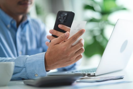 A man is using his cell phone to pay for something. He is holding a receipt in his hand photo