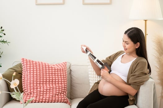 Pregnant woman holding ultrasound picture in living room at home photo