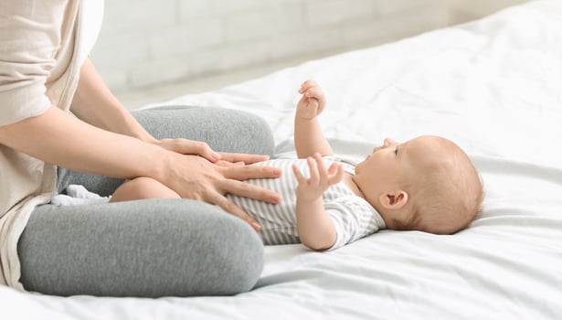 Baby healthcare. Woman massaging tummy of her son preventing colics, crop photo