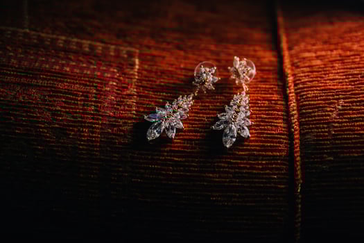A pair of earrings with a leaf design are sitting on a red cloth photo