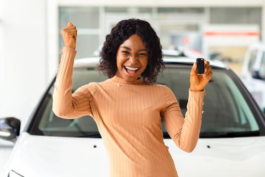 Happy Owner. Overjoyed Black Lady Holding Keys Of Her New Car After Buying, Cheerful African American Woman Standing Near Vehicle In Dealership Center And Raising Fist With Excitement, Copy Space photo