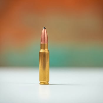 single gold-colored cartridge on a white surface photo