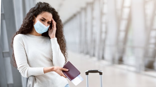 Flight Cancellation. Upset Young Woman Wearing Medical Mask Waiting At Airport, Frustrated Female Holding Passport And Tickets While Standing At Terminal With Sad Face Expression, Copy Space photo