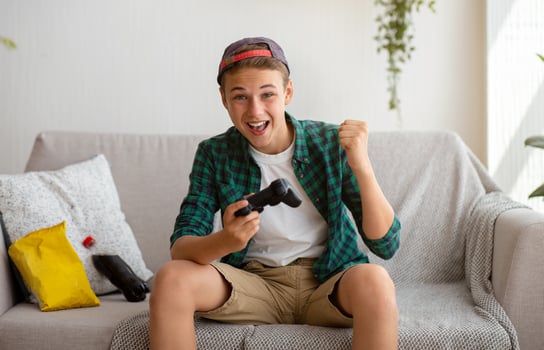 Positive teenager playing games at home, eating junk food, enjoying his free time photo