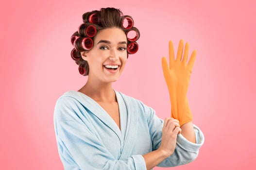 Happy Housewife Putting On Gloves Ready For Spring Cleaning Posing Over Yellow Studio Background. photo