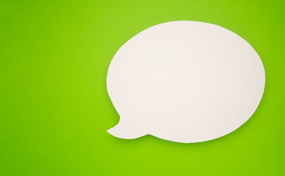 A blank white speech bubble over a light green background photo