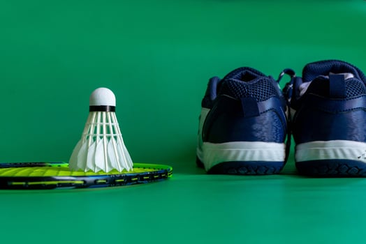 badminton rackets, shuttlecocks, and shoe placed against a vibrant green backdrop, showcasing sports gear photo