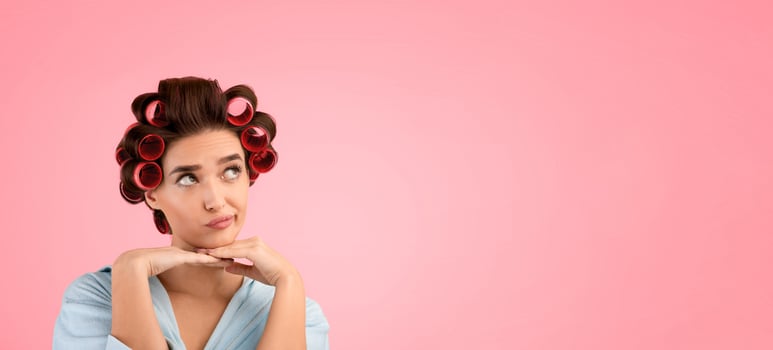 Thoughtful Female With Hair Curlers Thinking Holding Hands Near Face Looking Aside At Copy Space Over Yellow Studio Background. Beauty Care And Cosmetics Advertisement. Housewife's Thoughts photo