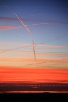Orange dusk with vapor trails over landscape silhouette photo