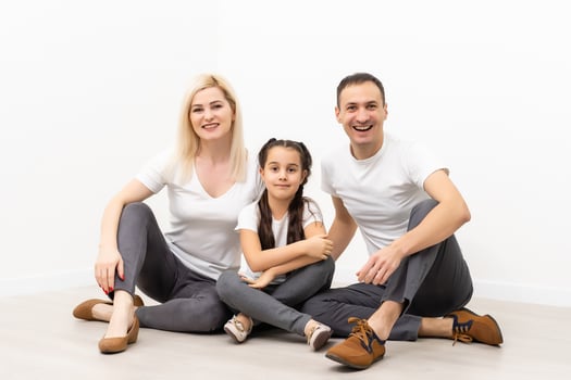 happy family father mother and children sitting on the floor in an empty white wall photo