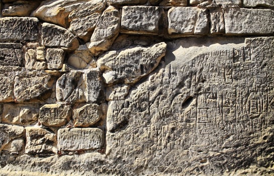 Old fieldstone wall with many scratches in sunlight photo