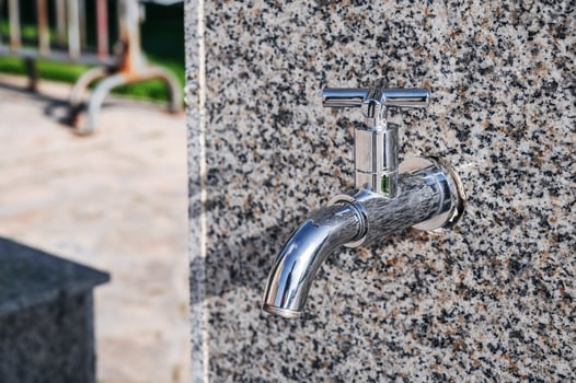 modern metal outdoor faucet with clean drinking water in park on the street in the city in summer photo