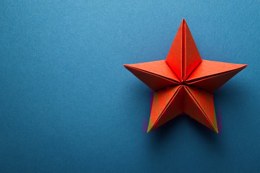 A red origami star on a blue background photo