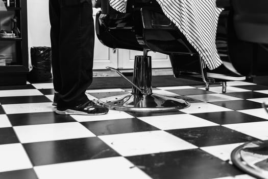 Haircut in a modern barbershop with classic black and white checkerboard floor photo