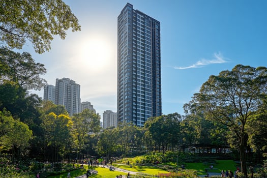 Modern green skyscraper with lush balconies overlooking urban skyline at sunset photo