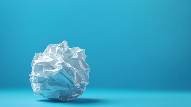 Crumpled White Paper Ball on blue background photo