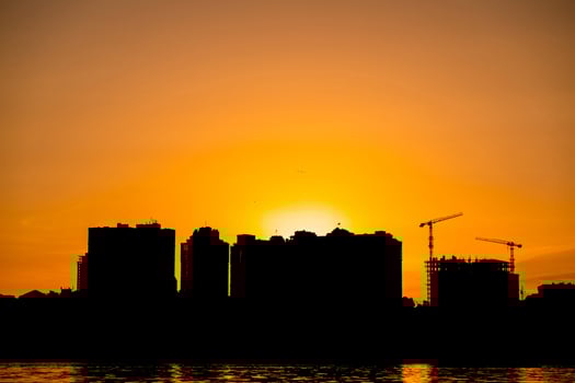 City skyline silhouette during sunset with cranes and buildings reflected in water photo