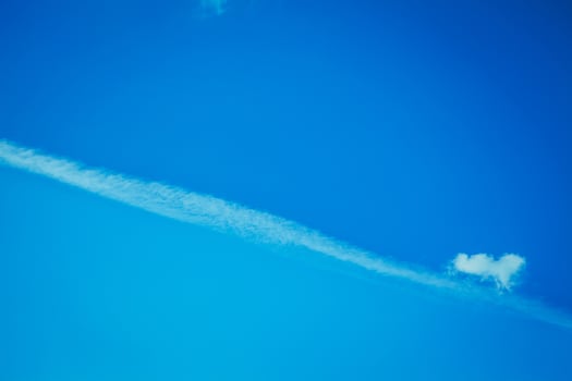 A single, thin cloud stretches across a bright blue sky photo