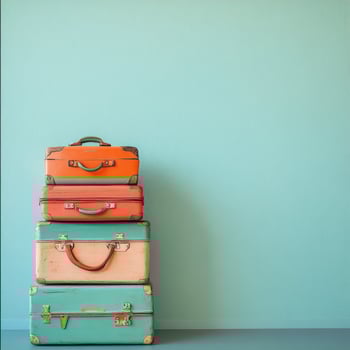 Vintage luggage stacked against a bright turquoise wall for a stylish travel display photo