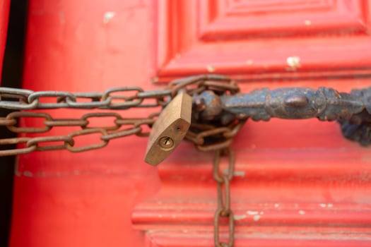 Closeup of metallic chains and locks in handles on red closed doors photo