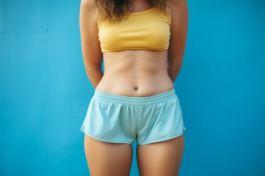 Fit woman in yellow crop top and blue shorts photo