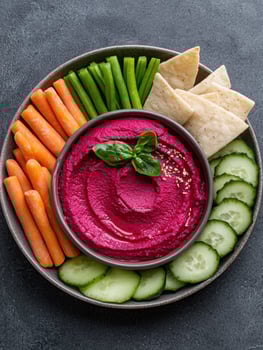 Vibrant beetroot hummus with assorted fresh vegetables and pita bread photo