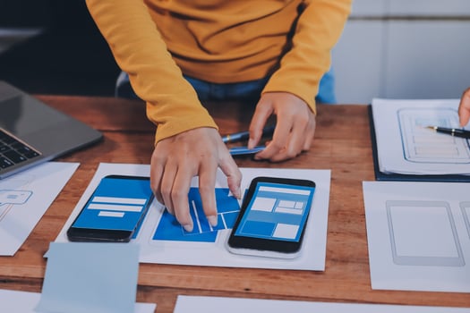 A person is using a smartphone and laptop on a table photo