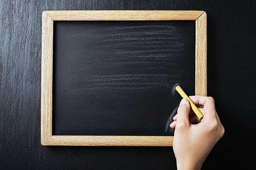 A person's hand holding a pencil and writing on a blackboard photo