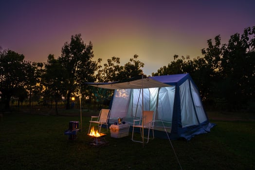 Camping tents at night, vintage cabin tents, antique oil lamps, retro chairs, and a group of camping tents with outdoor coffee-making facilities on wooden tables in a forest camping area in the forest photo