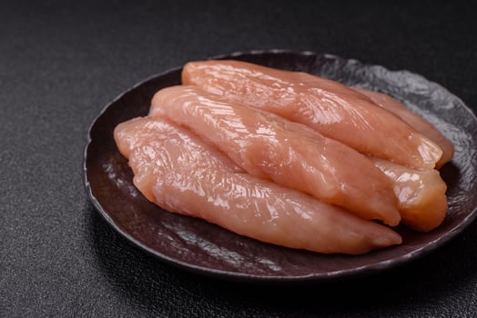 Raw chicken fillet cut into strips with spices and herbs photo