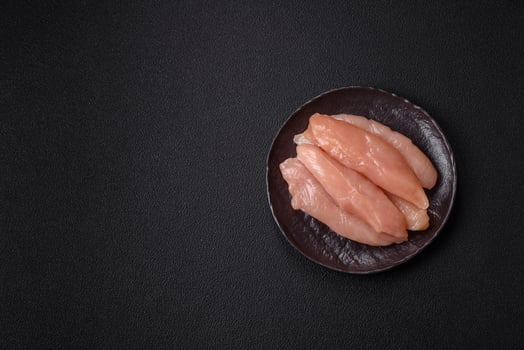 Raw chicken fillet cut into strips with spices and herbs photo