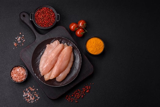 Raw chicken fillet cut into strips with spices and herbs photo