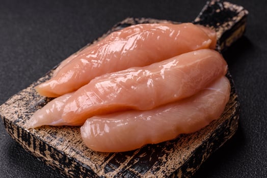 Raw chicken fillet cut into strips with spices and herbs photo