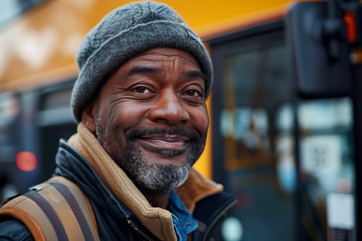 A man smiles while standing in front of a bus photo