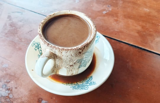 Hot chocolate flavored coffee in a white cup with green pictures. photo