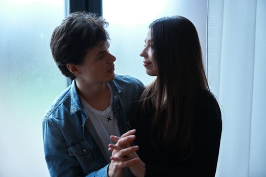 Young couple sharing a romantic moment indoors near a window in soft daylight photo